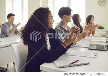 Group of a happy young diverse students applauding to lecturer during a lesson in classroom. 129800505