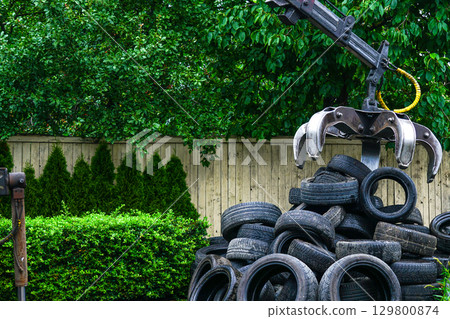 Industrial Grapple Loader Lifting Used Tires at Recycling Facility Outdoors Industrial Grapple Loader Lifting Used Tires at Recycling Facility Outdoors 129800874