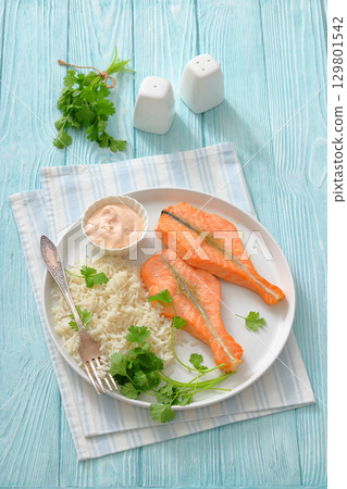 baked salmon steaks with rice, cilantro and sauce 129801542