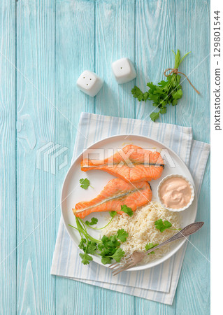 baked salmon steaks with rice, cilantro and sauce 129801544