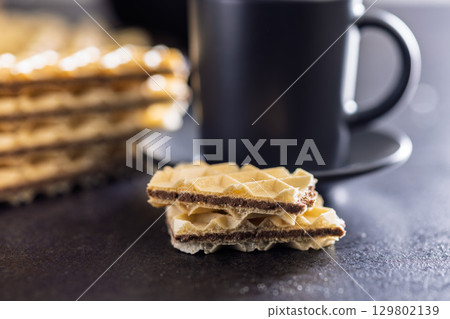 Sweet crispy wafers on black table. 129802139