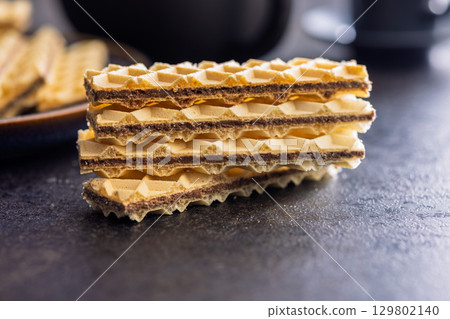 Sweet crispy wafers on black table. Sweet crispy wafers on black table. 129802140