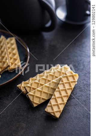Sweet crispy wafers on black table. Sweet crispy wafers on black table. 129802141
