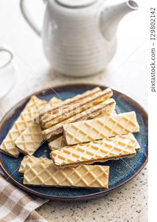 Sweet crispy wafers on plate on kitchen table. Sweet crispy wafers on plate on kitchen table. 129802142
