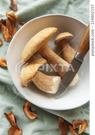 Fresh mushrooms with knife in bowl preparing for cooking Fresh mushrooms with knife in bowl preparing for cooking 129802157