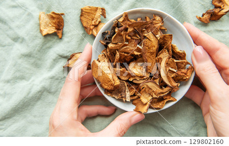 Chef holding bowl of dried mushrooms on green tablecloth Chef holding bowl of dried mushrooms on green tablecloth 129802160
