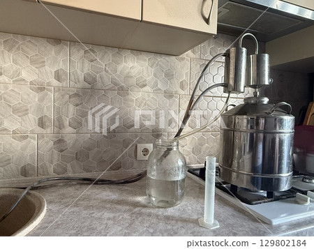Distilling alcohol using moonshine still in kitchen 129802184