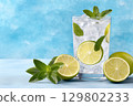 Refreshing mojito cocktail with lime, mint and ice cubes on blue background 129802233