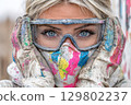 Painter woman wearing protective glasses and mask covered in paint 129802237