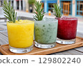 Colorful frozen cocktails garnished with rosemary sprigs on wooden tray 129802240