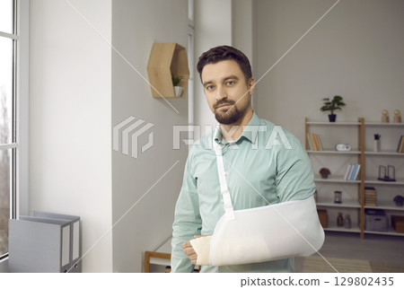 Handsome young man with with plaster on his broken arm Handsome young man with with plaster on his broken arm 129802435