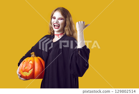 Happy woman in spooky costume isolated on yellow background inviting you to Halloween party 129802514