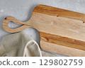 Empty wooden cutting board and linen napkin on stone grey surface 129802759