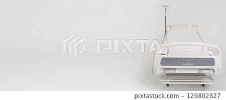 An Empty Hospital Bed Positioned on a Clean White Background That Represents Healthcare 129802827