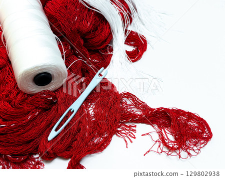 Red and white yarn with needle on white background for crafting and knitting projects Red and white yarn with needle on white background for crafting and knitting projects 129802938