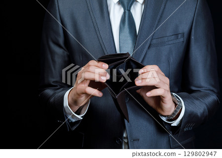 Empty wallet held by a businessman in a suit 129802947