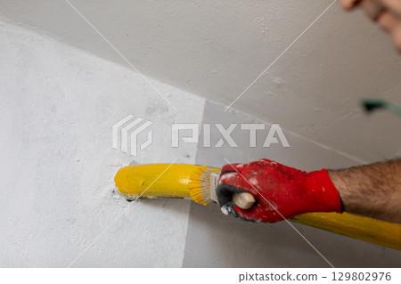 Painting the Wall with a Yellow Roller in a Home Renovation Project with Care and Precision Painting the Wall with a Yellow Roller in a Home Renovation Project with Care and Precision 129802976