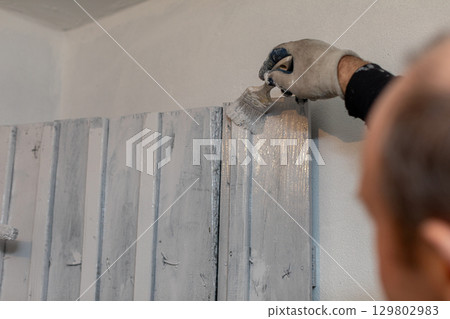 Individual Skillfully Applying Paint to Rustic Wall Panels for a Stylish Aesthetic Appeal Individual Skillfully Applying Paint to Rustic Wall Panels for a Stylish Aesthetic Appeal 129802983