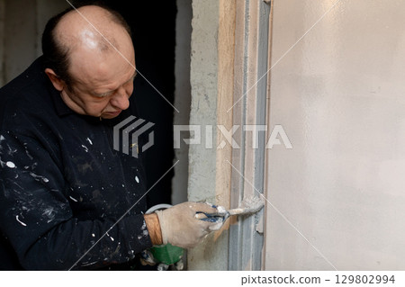 A Skilled Worker Diligently Applying the Final Finishing Touches in Construction Projects 129802994