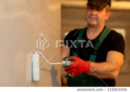 A Skilled Professional Painter Is Currently at Work Applying a Fresh Coat of Paint to Surfaces 129803000