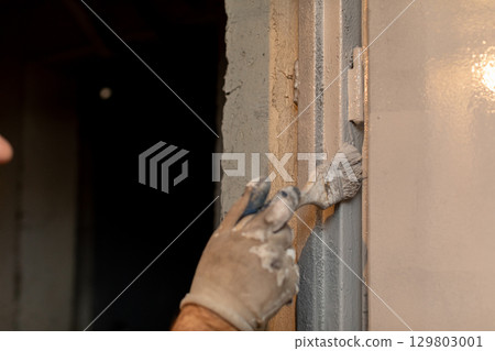 A skilled professional handyman methodically applying plaster during an interior renovation project 129803001