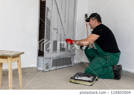 A Skilled Painter is Working Diligently on Wall Renovation in a Modern Interior Space A Skilled Painter is Working Diligently on Wall Renovation in a Modern Interior Space 129803004
