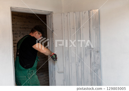 A skilled craftsman installs a door in a modern space, showcasing expert craftsmanship 129803005