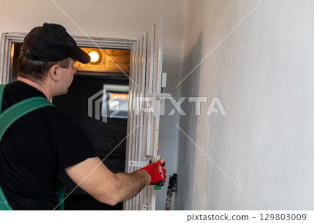A professional worker is carefully adjusting a ladder in a space that is being renovated 129803009