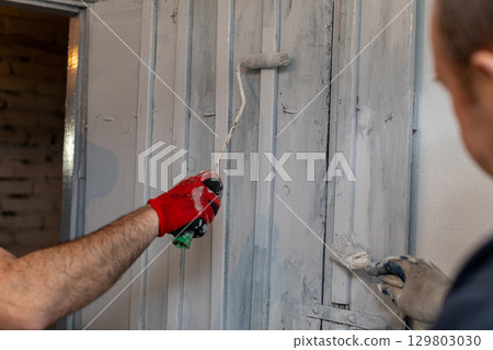 A HandsOn Painting Activity Involves Using a Roller and a Brush During a Renovation Project 129803030