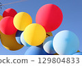 A beautiful display of colorful balloons floating against a bright and clear blue sky 129804833