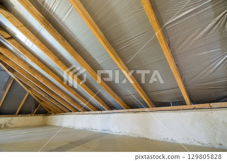 Attic of a building with wooden beams of a roof structure. 129805828