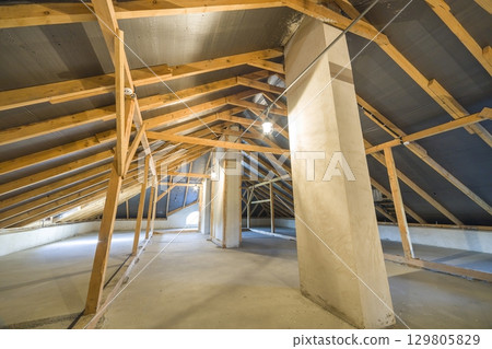 Attic of a building with wooden beams of a roof structure. Attic of a building with wooden beams of a roof structure. 129805829
