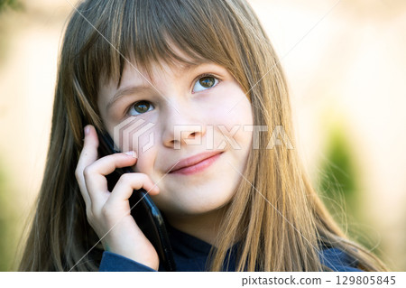 Portrait of pretty child girl with long hair talking on cell phone. Little female kid communicating using smartphone. Children communication concept. 129805845