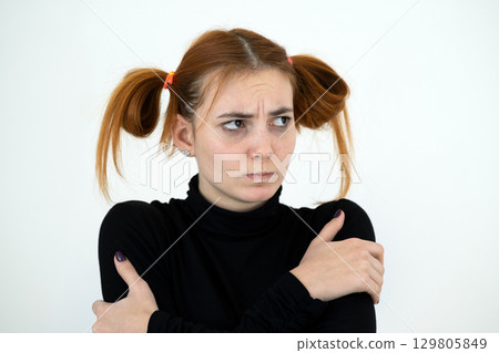 Closeup portrait of a sad redhead teenage girl with childish hairstyle looking offended isolated on white backround. Closeup portrait of a sad redhead teenage girl with childish hairstyle looking offended isolated on white backround. 129805849