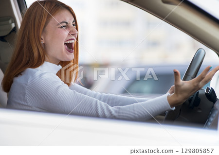 Closeup portrait of pissed off displeased angry aggressive woman driving a car shouting at someone with hand fist up. Negative human expression consept. 129805857