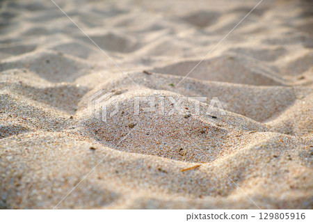 Close up of clean yellow sand surface covering seaside beach illuminated with day light. Travel and vacations concept 129805916