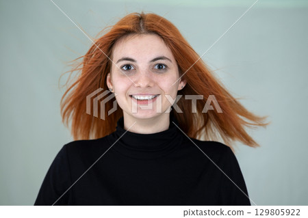 Close up portrait of pretty redhead girl with long wavy hair blowing on the wind. 129805922