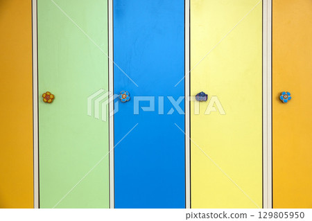 Close up of colorful lockers doors with funny animals as door knobs in day care school. 129805950