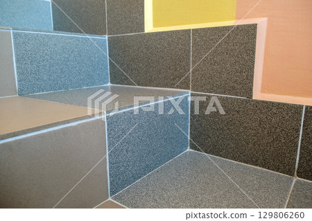 Wide staicase covered with ceramic tiles indoors in a house interior. 129806260