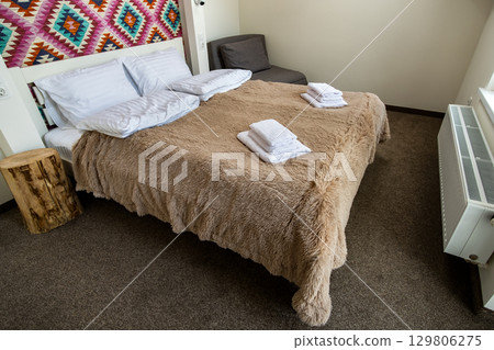 Interior of a spacious hotel bedroom with fresh linen on a big double bed. Cozy contemporary room in a modern house. Interior of a spacious hotel bedroom with fresh linen on a big double bed. Cozy contemporary room in a modern house. 129806275