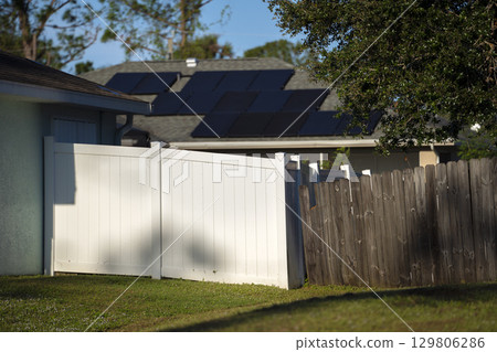 White vinyl picket fence on green lawn surrounding property grounds for backyard protection and privacy 129806286