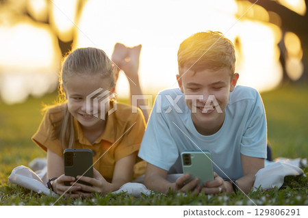Portrait of positive happy children texting with their friends on cellphones. 129806291