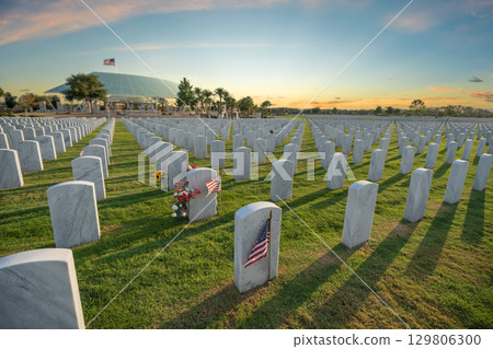 Sarasota National Cemetery with many white headstones on green grass lawn at sunset. Memorial Day concept 129806300