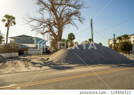 Cleanup efforts after hurricane in Florida. Piles of broken furniture, household debris and construction waste line streets of Manasota Key, showing severe impact on local homes and infrastructure 129806322