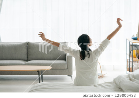 Rear view of a woman stretching after waking up in the morning 129806458