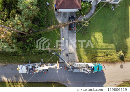 Electrical service company restoring power repairing damaged power lines after hurricane in Florida suburban area 129806519