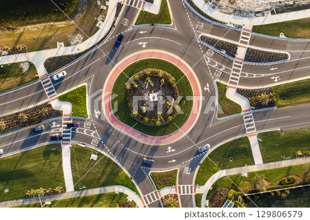 Aerial view of roundabout intersection on American road with moving traffic cars. Urban circular transportation crossroads 129806579