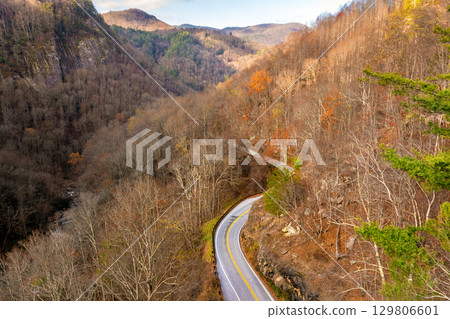Scenic drive through Tennessee Appalachians at sunset in fall season. Car traveling on curvy forest road under vibrant autumn foliage 129806601