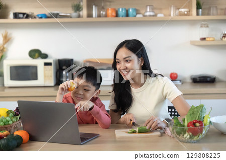 Cooking Together. Mother and son preparing healthy meal while watching online recipe. 129808225