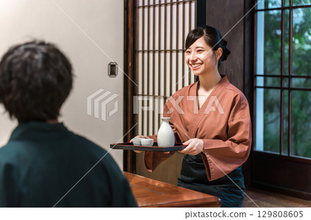 A female inn staff member serving food at a Japanese inn or Kappo restaurant, a waitress or landlady A female inn staff member serving food at a Japanese inn or Kappo restaurant, a waitress or landlady 129808605